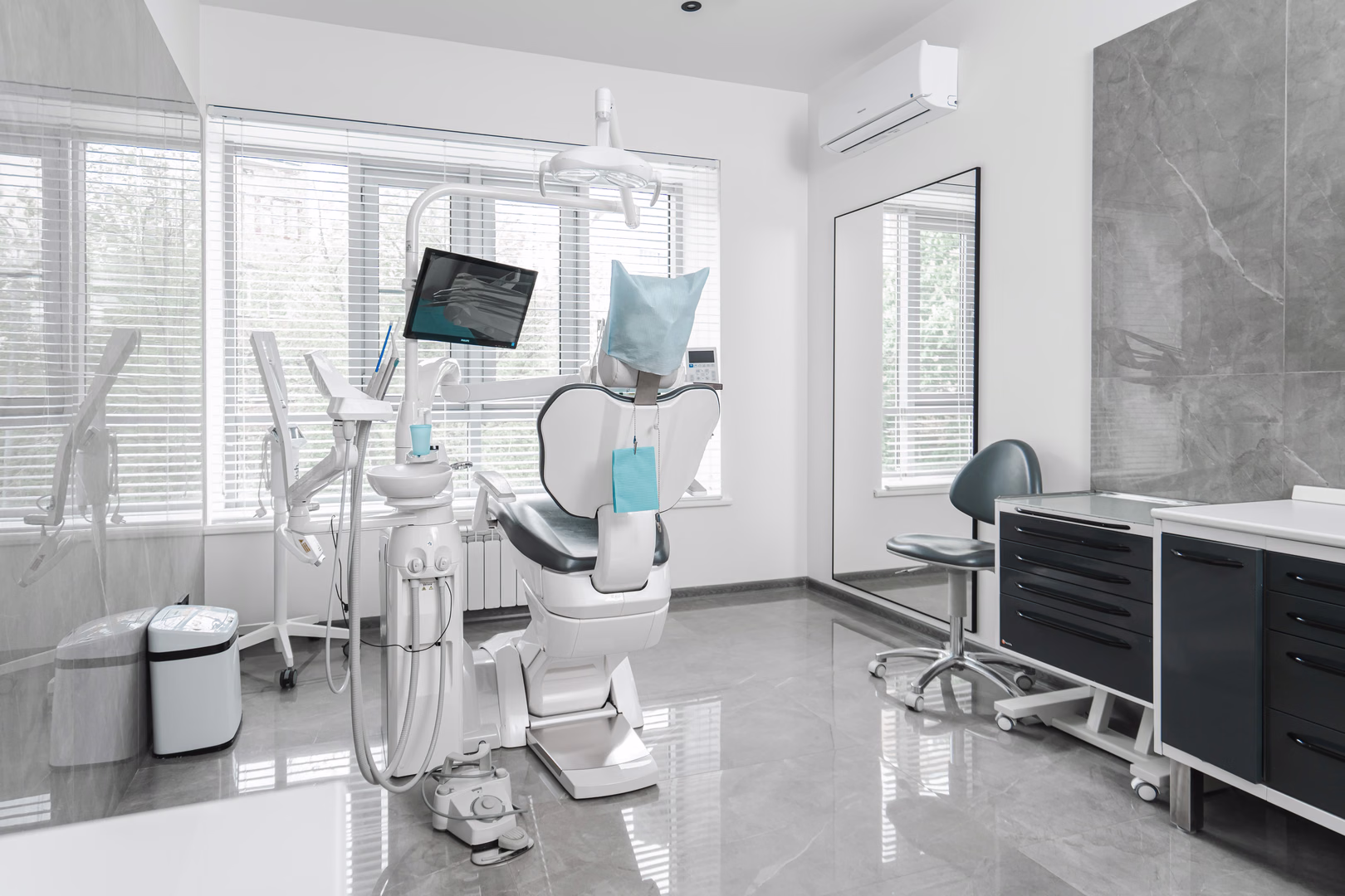 Стоматологический кабинет Dental Smile с тёмным креслом у окна и чёрной рабочей тумбой