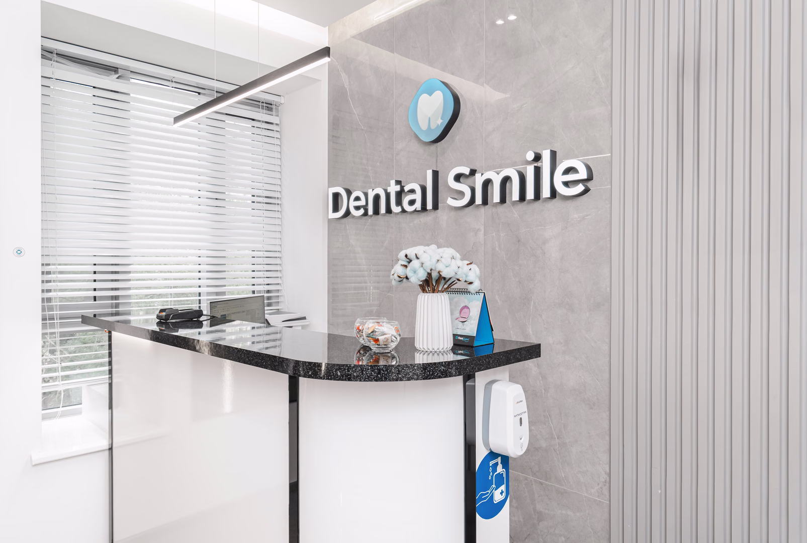 Стойка регистрации Dental Smile с чёрной столешницей, логотипом на стене и белыми цветами