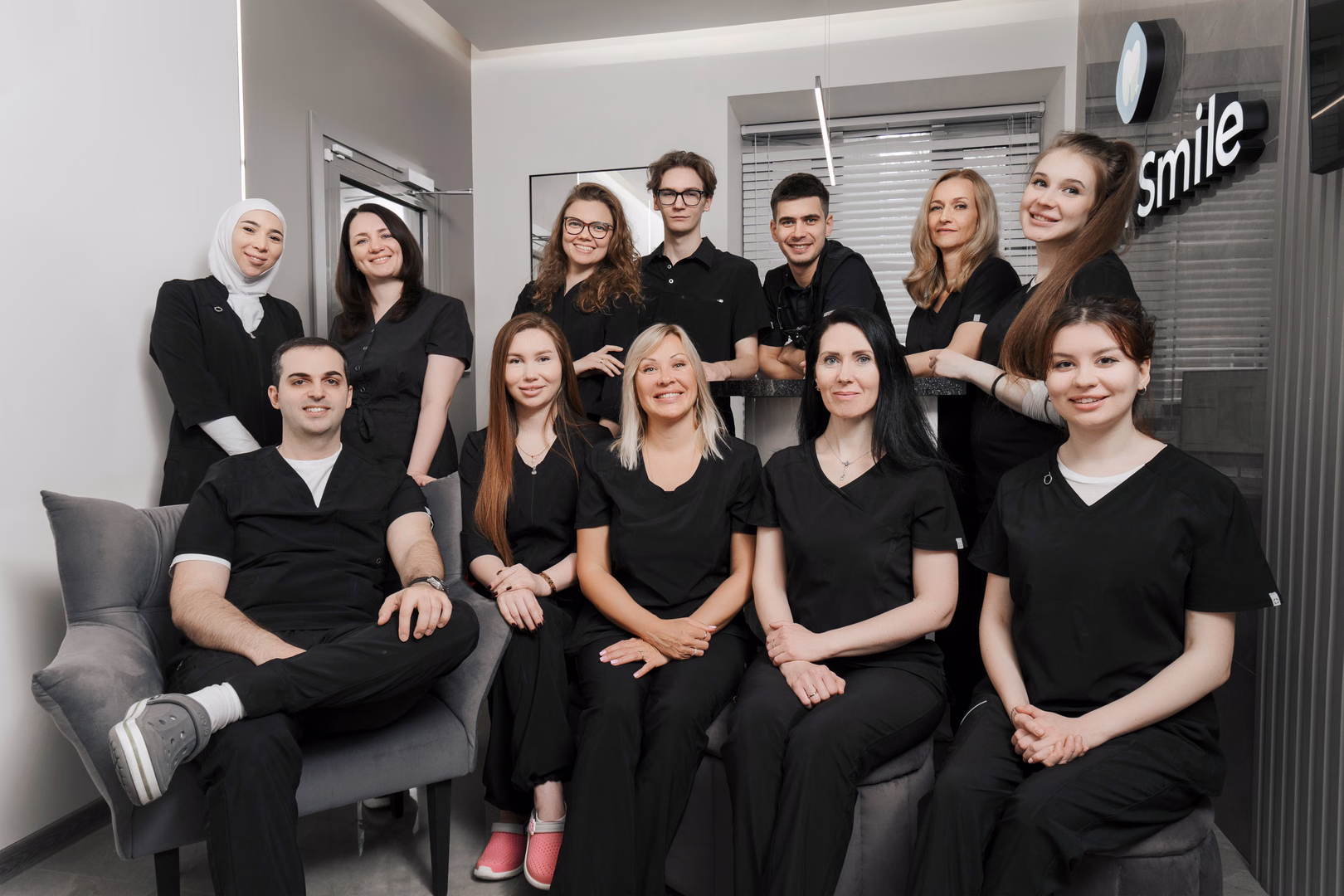 Групповой портрет команды Dental Smile: сотрудники сидят и стоят у стойки регистрации