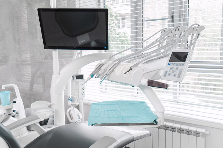 Монитор и блок инструментов над стоматологическим креслом у окна в Dental Smile
