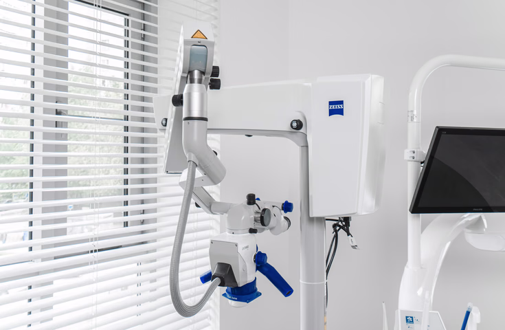 Крепление и корпус стоматологического микроскопа Dental Smile рядом с монитором у окна