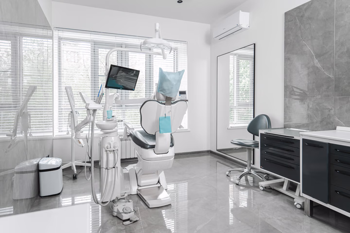 Стоматологический кабинет Dental Smile с тёмным креслом у окна и чёрной рабочей тумбой