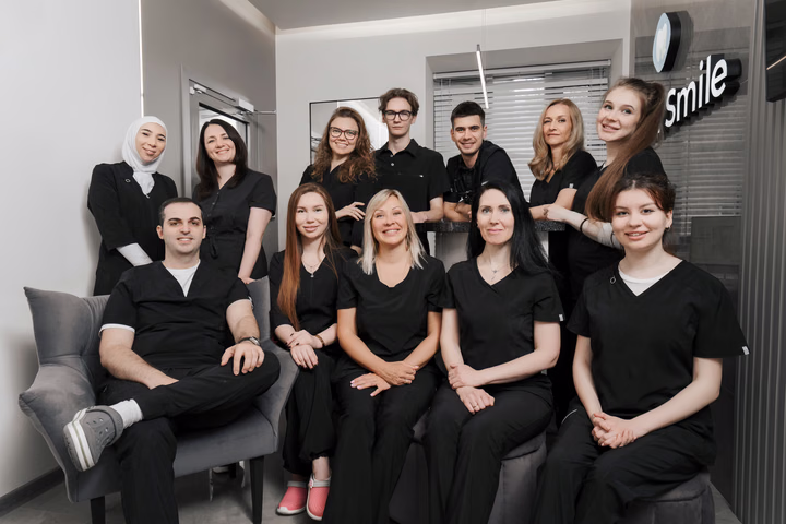 Групповой портрет команды Dental Smile: сотрудники сидят и стоят у стойки регистрации