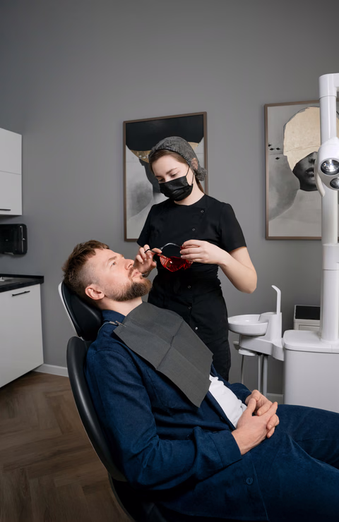 Ассистент Weeksmile держит защитные очки перед пациентом в стоматологическом кресле
