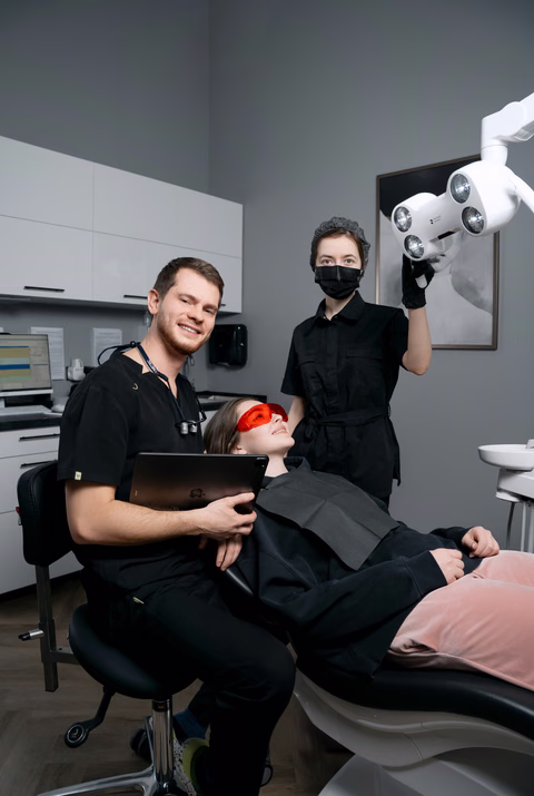 Стоматолог и ассистент Weeksmile рядом с пациенткой в оранжевых защитных очках